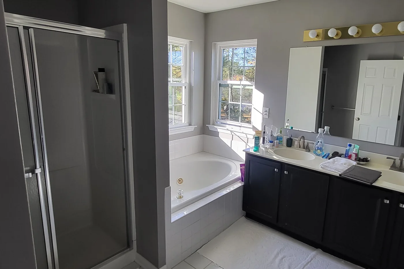 The primary bathroom before the remodel, with a shower too small to enjoy, an unused tub taking up space, and dated finishes under dim lighting.